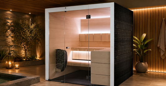 Modern cube-style outdoor cabin sauna in thermo-spruce with a glowing glass front at dusk