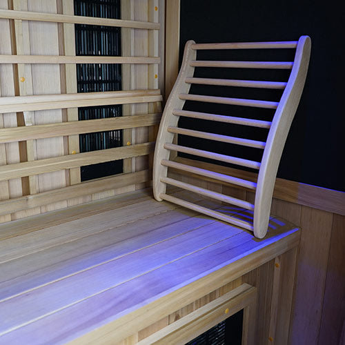 Curved ergonomic cedar sauna backrest on a bench with LED accent lighting and infrared panels behind